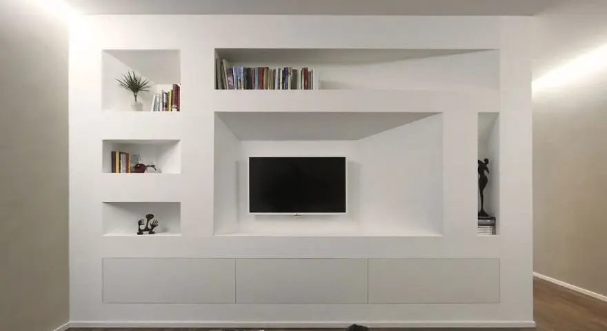 Parete attrezzata moderna con nicchie per libri e TV, realizzata in cartongesso doppia lastra, con mobili contenitori a scomparsa.