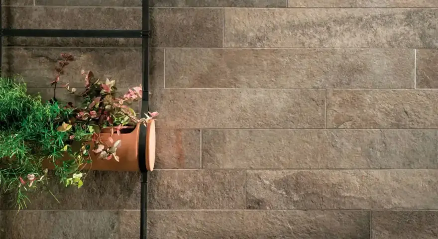 Un muro esterno rivestito con lastre effetto pietra, con un vaso di piante appeso. Ottime idee per coprire muro esterno con stile naturale.