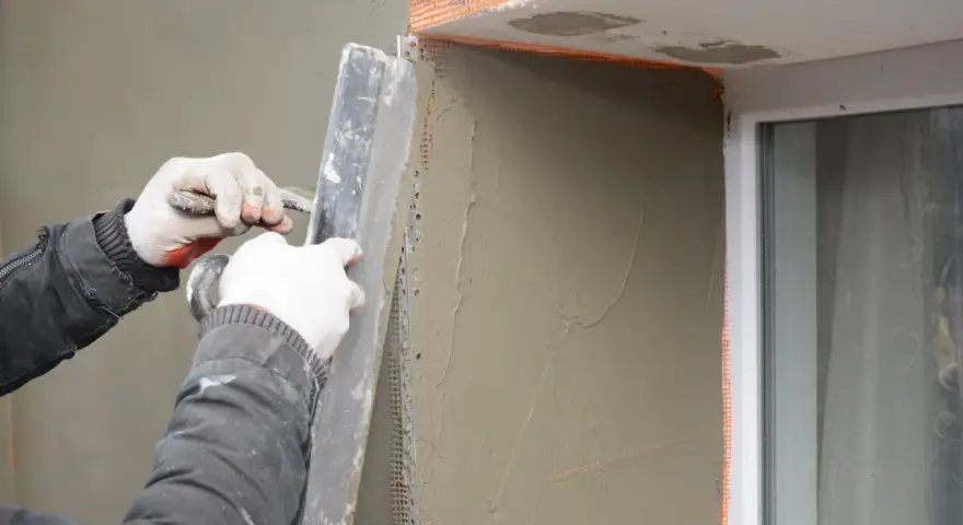 Lavori di intonacatura attorno alle finestre, con un cappotto che protegge le spallette. Si nota lo spessore dello strato di intonaco.