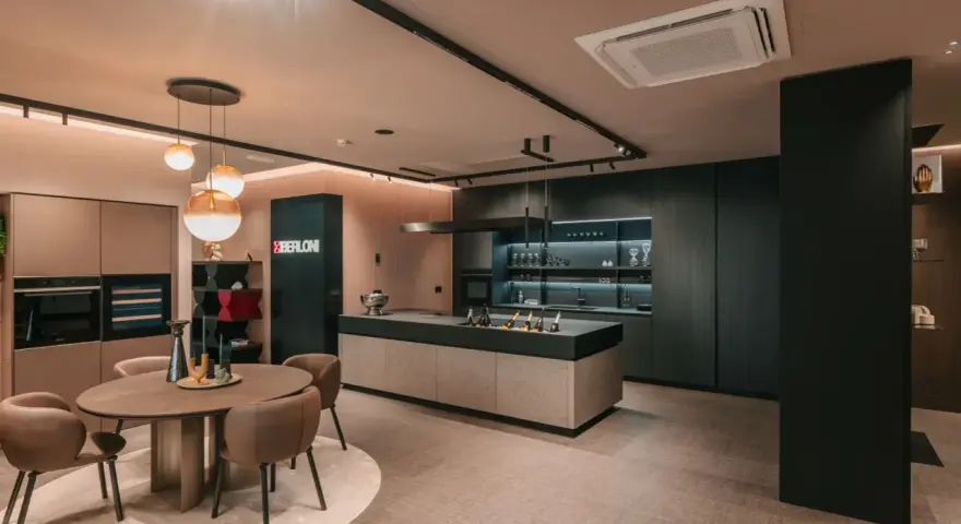 Elegante cucina scura con isola centrale e un tavolo rotondo. Il pavimento chiaro crea un contrasto moderno e luminoso.