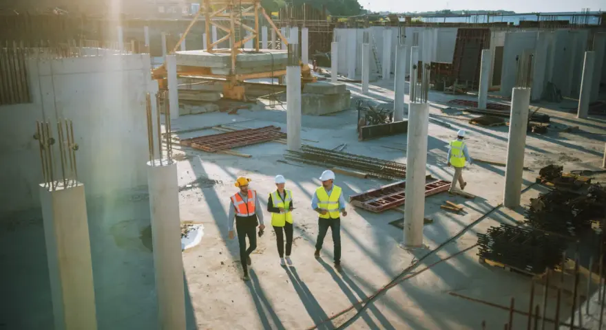 Un cantiere edile con operai in giubbotti ad alta visibilità. Il general contractor cos'è? È chi coordina i lavori, gestendo fornitori e tempi per un progetto di successo.