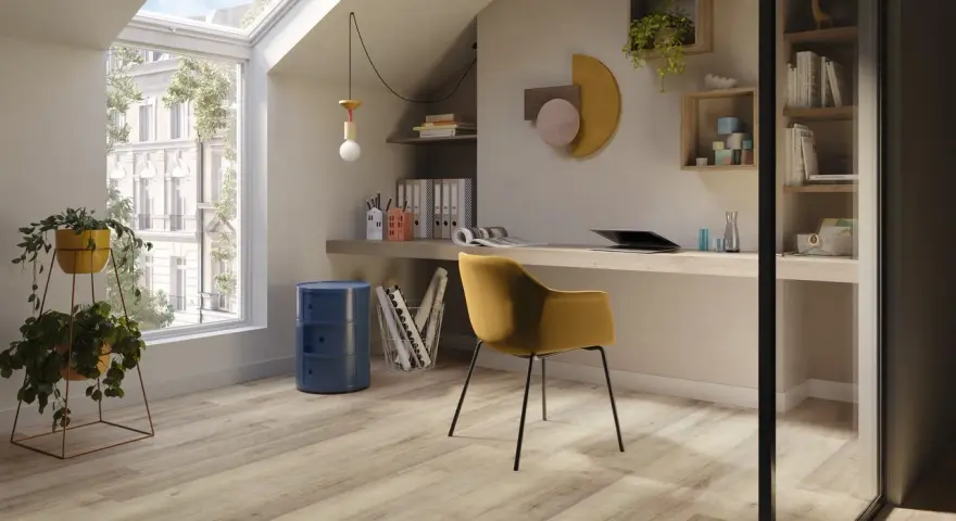Luminoso studio mansardato con scrivania, sedia gialla e un elegante **pavimento polvere di pietra** che riflette la luce naturale.