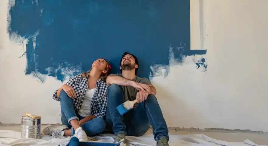 Coppia seduta sul pavimento, guarda in alto verso un muro dipinto di blu. Stacco tra parete e soffitto si o no?