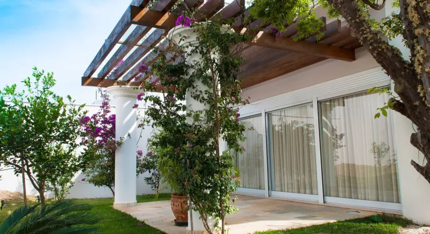 Un pergolato in legno e piante rampicanti per decorare muri esterni giardino.