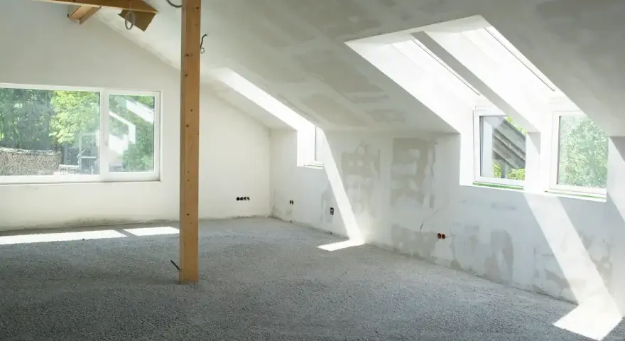 Sottotetto in costruzione con pareti in cartongesso e un pavimento in materiale granulare, pronto per essere calpestabile.