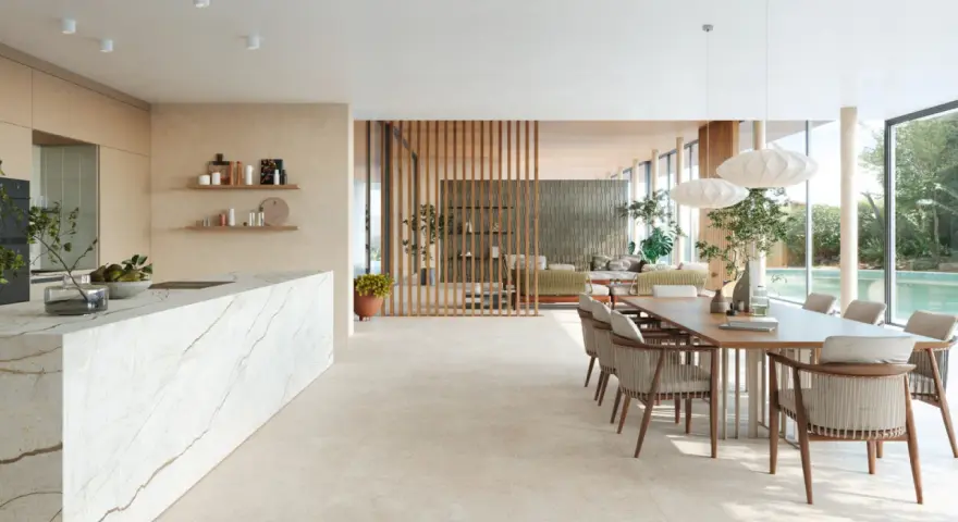 Ampio open space con cucina moderna, isola in marmo e zona pranzo. Pavimenti diversi creano continuità visiva tra gli ambienti.