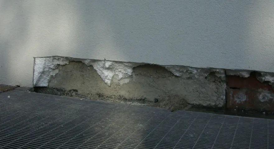 Dettaglio di un muro con isolamento danneggiato, mostrando la differenza tra polistirolo e polistirene espanso.