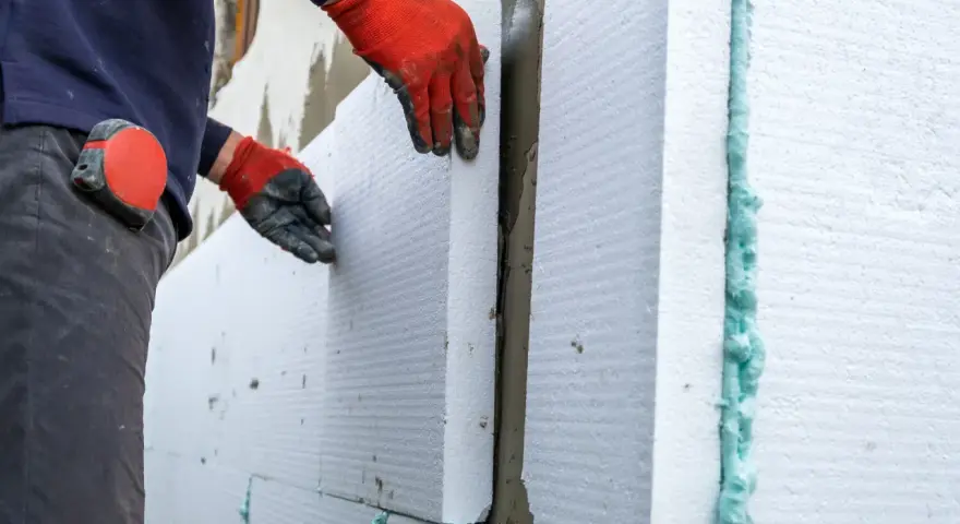Operaio posa pannelli isolanti per cappotto termico, attenzione alle fughe e alle soglie per evitare ponti termici.