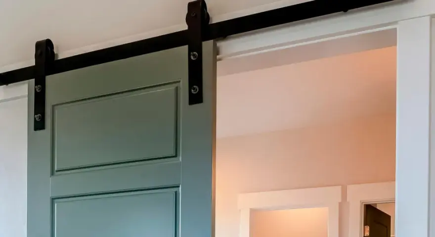 Trasformare porta battente in scorrevole: una porta verde acqua con binario nero, un'elegante soluzione moderna per ottimizzare gli spazi.