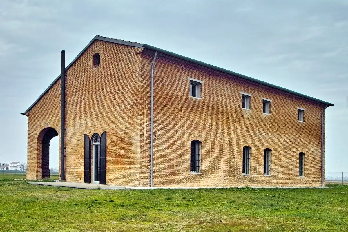 Edificio in mattoni con tetto spiovente, camino e un grande arco. Potrebbe essere una propriet&agrave; con categoria catastale A6, un tempo adibita a stalla o fienile.