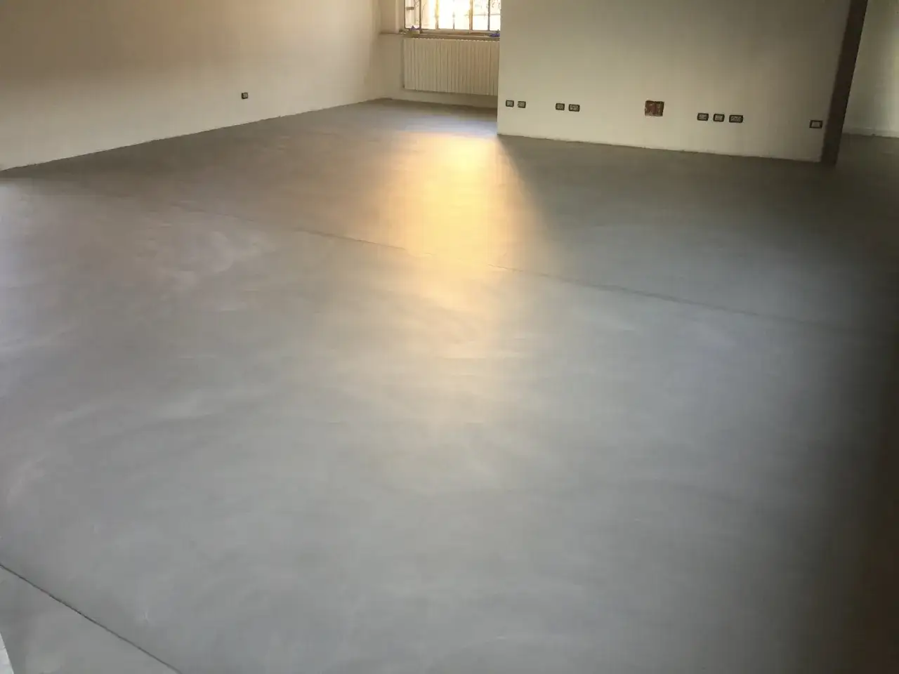 Pavimenti senza fughe: un'elegante continuità che nasconde pro e contro. Luce dorata illumina questo moderno pavimento in resina.