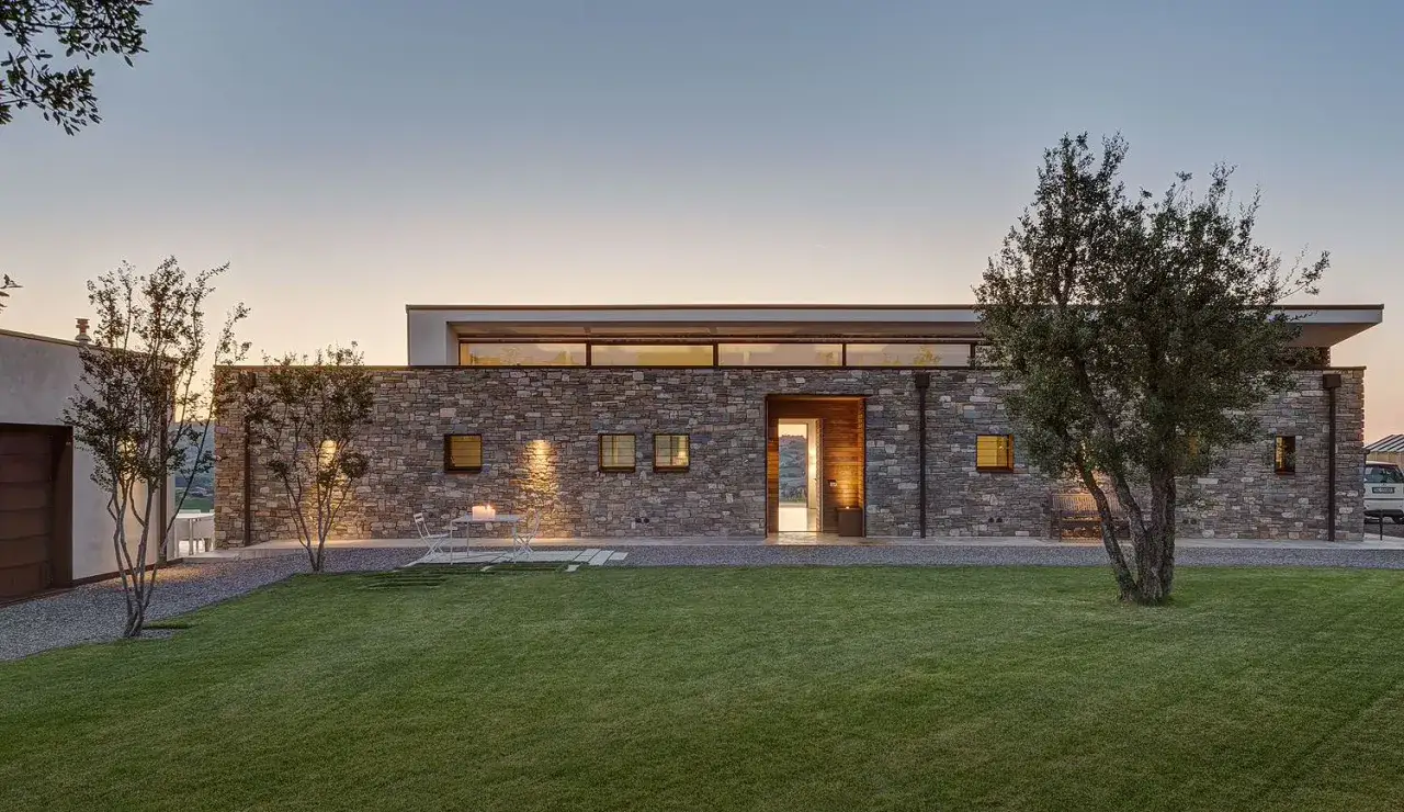 Villetta moderna in pietra, con ampio giardino e ingresso illuminato. Un'idea di quanto costa costruire una villetta di 120 mq.