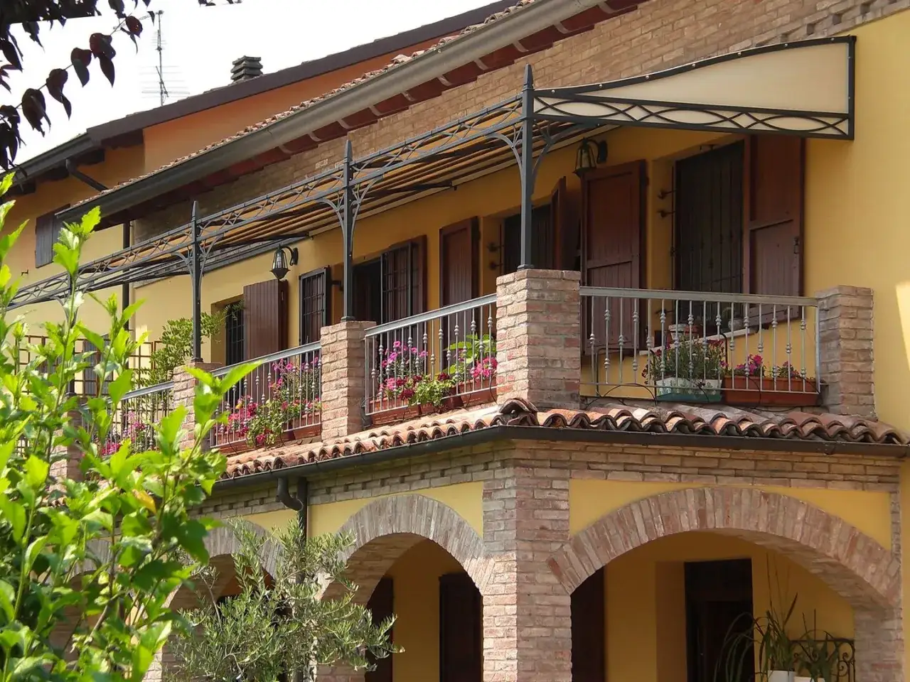 Il montaggio scossalina balcone protegge la facciata. Fioriere colorate adornano il parapetto in ferro battuto.