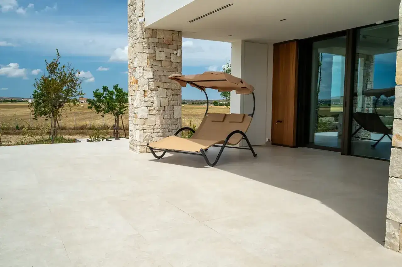 Pavimenti chiari e luminosi per una casa al mare, con sdraio e vista sulla campagna.