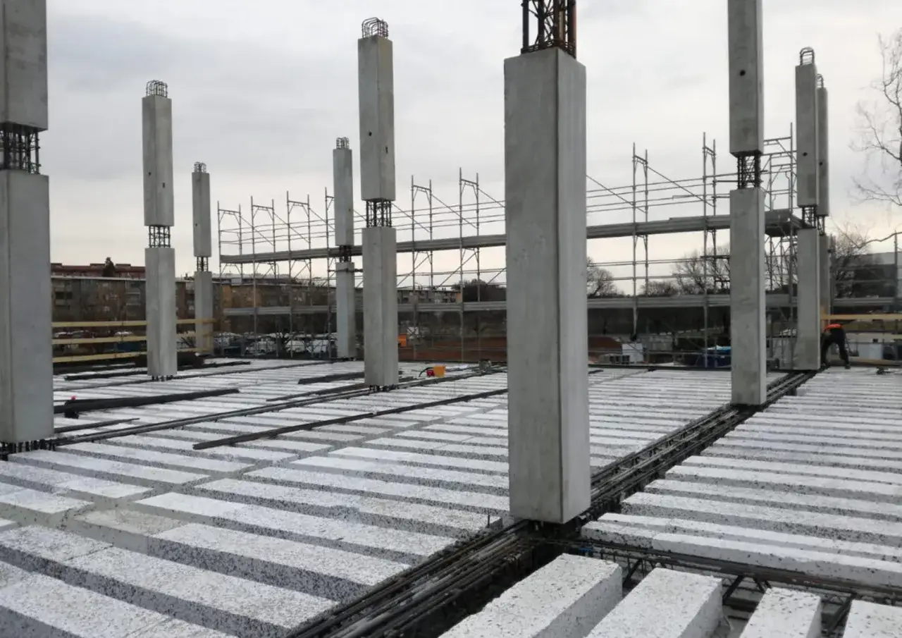 Costruzione in corso con pilastri in cemento e solai prefabbricati in attesa di completamento.