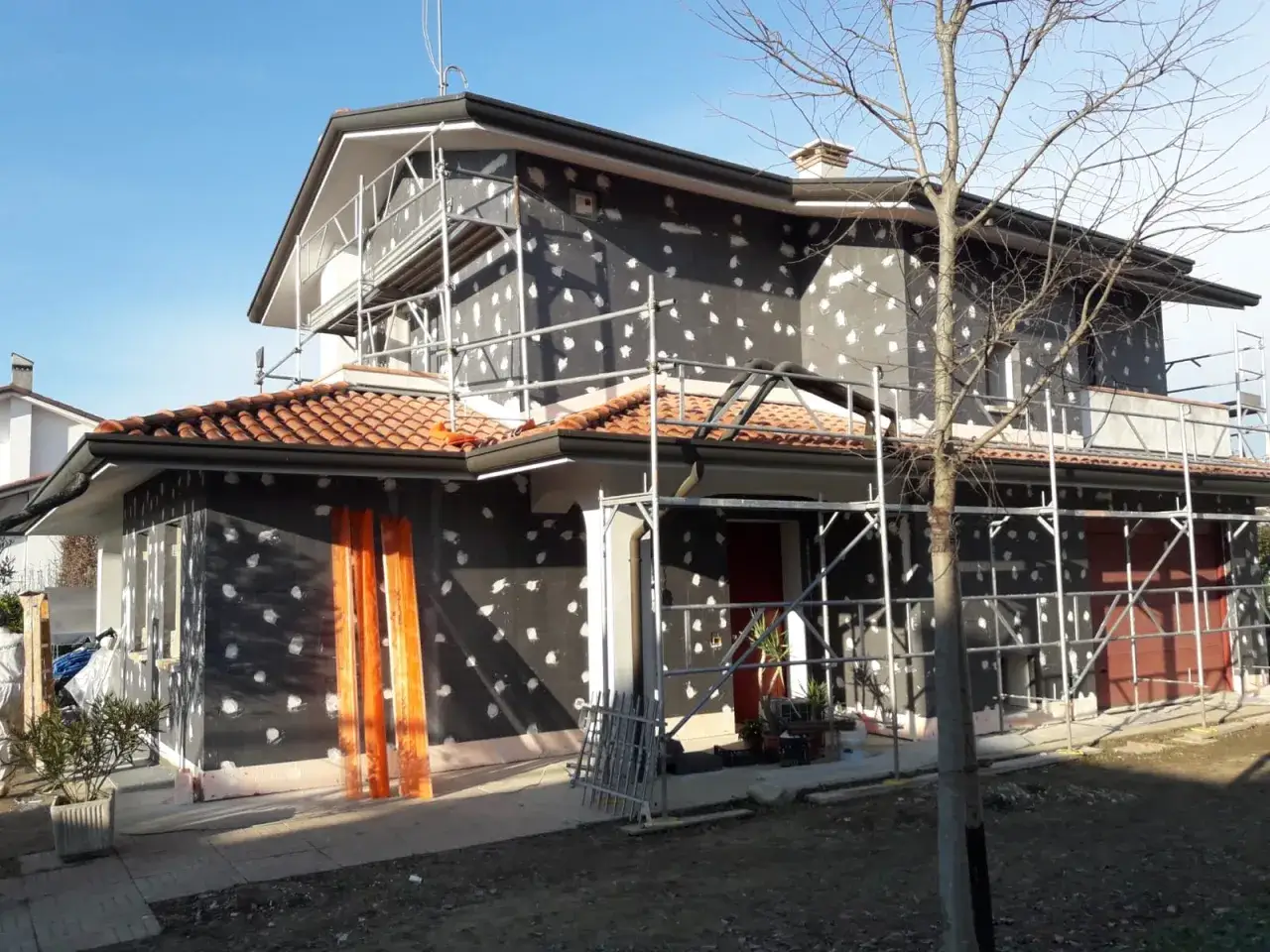 Casa in ristrutturazione con cappotto termico in materiale EPS. L'edificio è circondato da ponteggi.