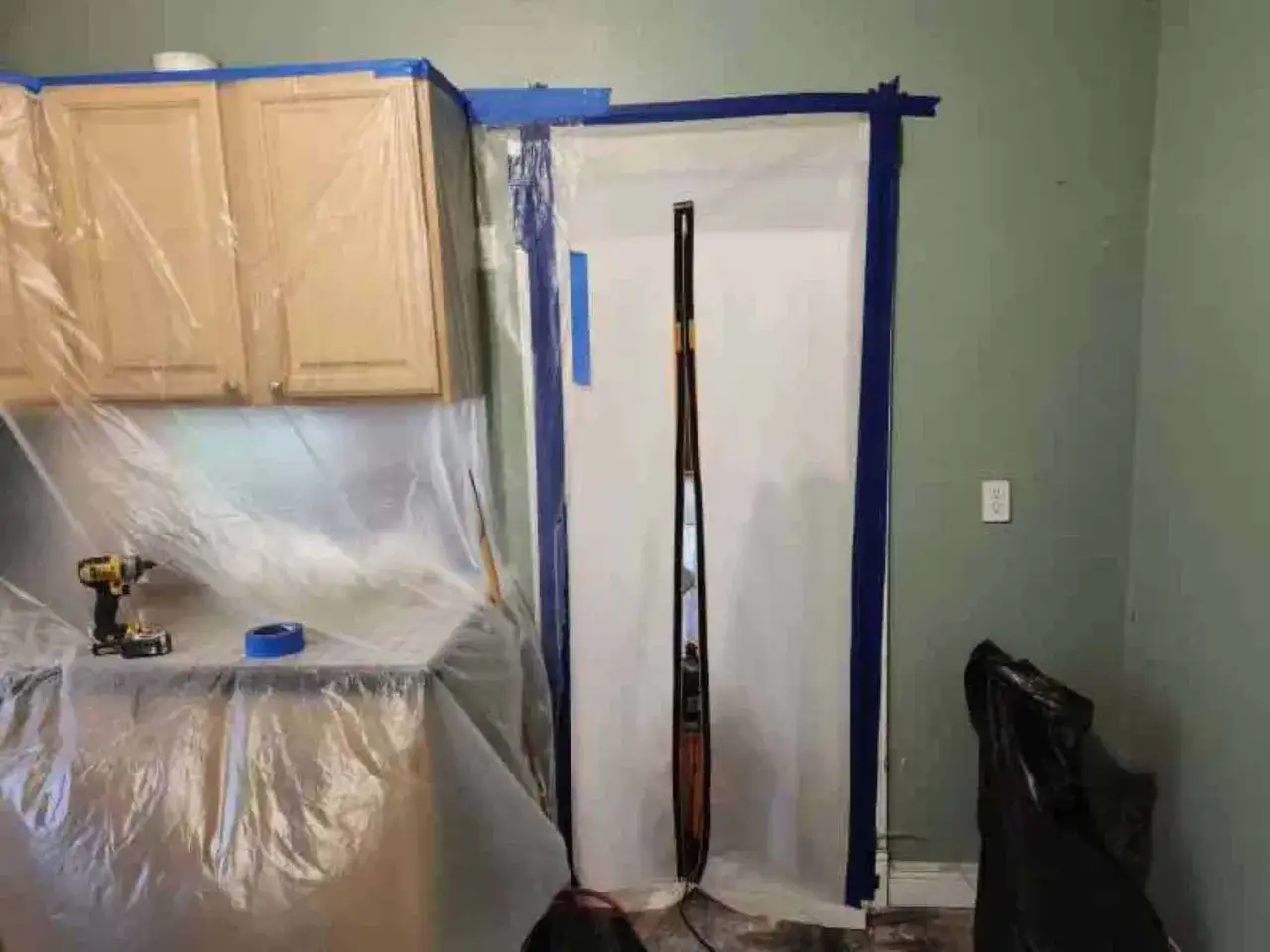 Preparazione per il trattamento antimuffa prima di pitturare: mobili coperti, nastro blu e attrezzi pronti.