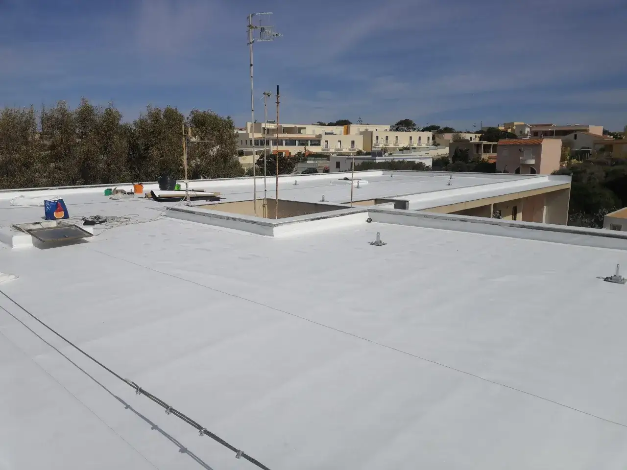 Lavori in corso per impermeabilizzare il tetto senza rifarlo. La nuova guaina bianca riflette il sole, mantenendo l'edificio fresco.