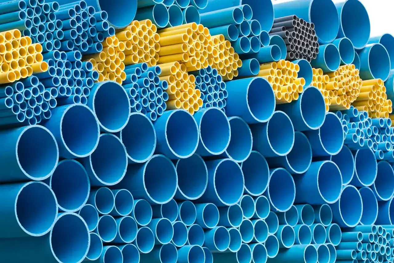 Pile di tubi in polipropilene, verdi e blu, con diverse dimensioni e diametri.