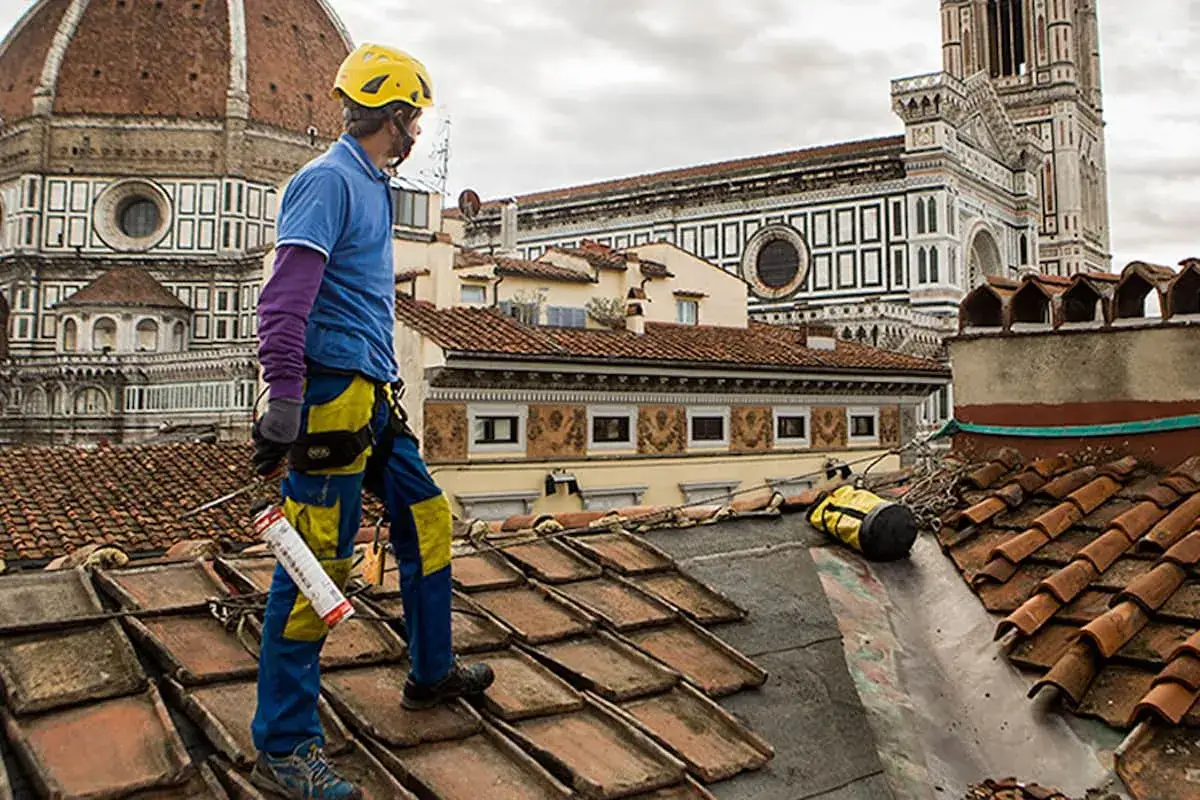 Operaio sul tetto di Firenze, valuta il costo coibentazione tetto esistente. Lavori in quota con vista Duomo.