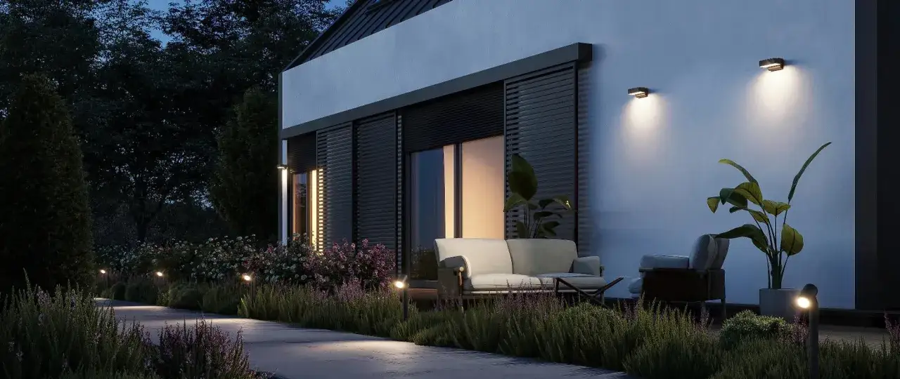 Illuminazione soffusa per decorare muri esterni giardino, creando un'atmosfera accogliente con piante e arredi da esterno.