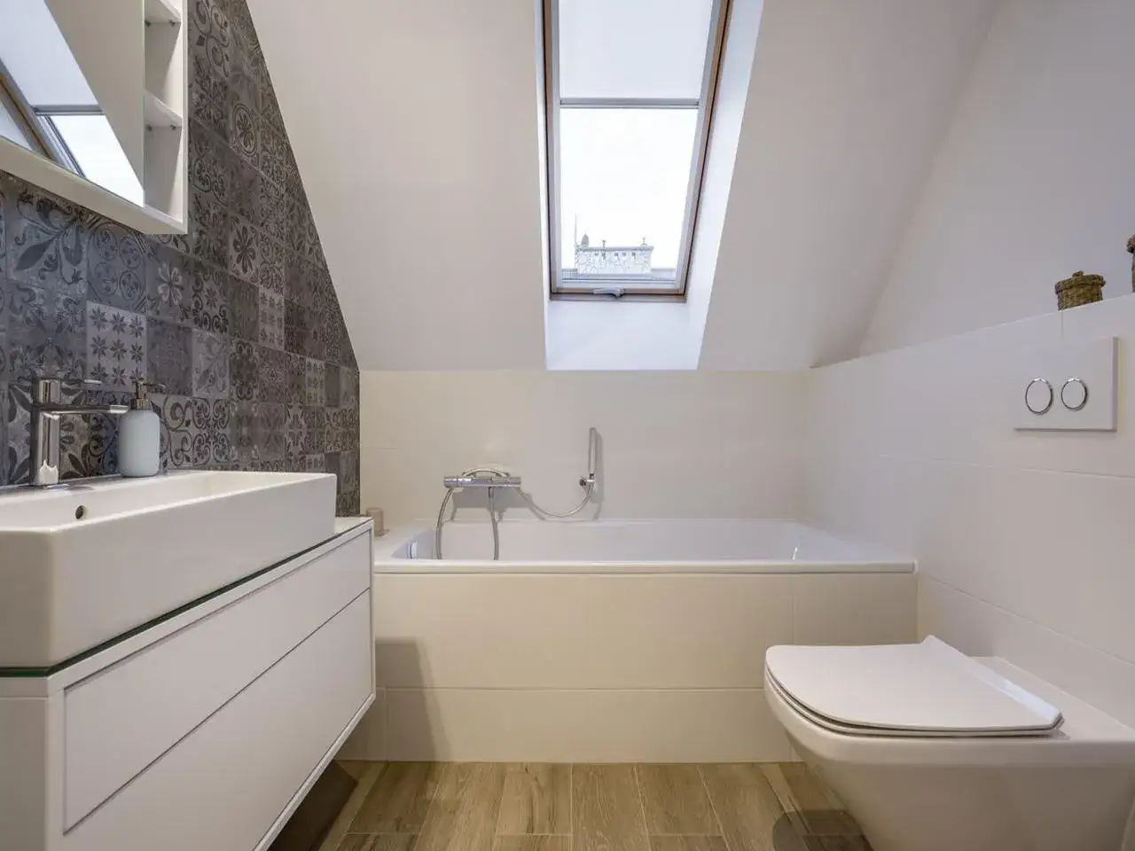 Bagno nel sottotetto non abitabile con vasca, lavabo moderno e WC. Tetto spiovente con lucernario.